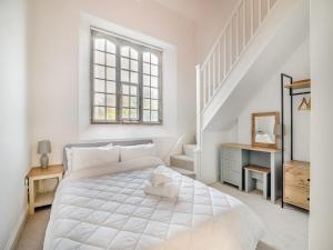 a white bedroom with a bed and a staircase at Old School Retreat in Puddletown