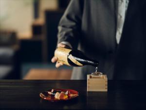 a person holding a bottle of wine next to a plate of food at nol kyoto sanjo in Kyoto