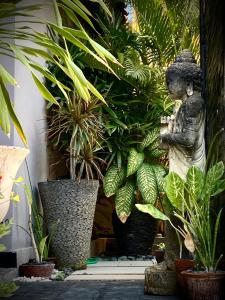 a statue of a person standing next to plants at Amalika Private Pool Villa Central to Everything in Gili Trawangan