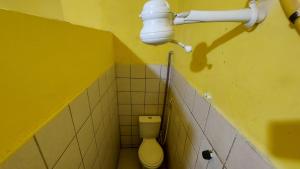 a yellow bathroom with a toilet and a light at Pousada Bomfim in Maceió