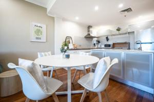 una cucina e una sala da pranzo con tavolo e sedie bianchi di Light Resort Style Haven in Darling Harbour a Sydney