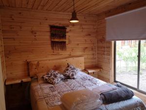 a bedroom with a bed in a log cabin at Rukawe Quillon in Quillón +65 photos