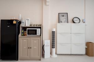 a kitchen with a black refrigerator and a microwave at Yimwhan House 02, Ayutthaya old town in Phra Nakhon Si Ayutthaya