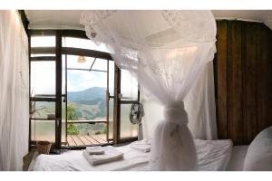 Schlafzimmer mit einem weißen Bett und einem großen Fenster in der Unterkunft The buh de (เดอะบูห์เดอะ) 