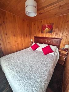 een slaapkamer met een bed met rode kussens bij Cabañas Emma Maicolpue in Osorno