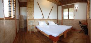 Eskapo Verde Resort Moalboal في باديان: غرفة نوم مع سرير أبيض كبير في غرفة