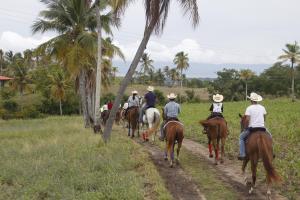 a group of people riding horses down a dirt road at Eskapo Verde Lodge Moalboal in Badian