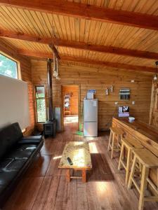 Sala de estar de una cabaña de madera con sofá y mesa en Rukawe Quillon en Quillón