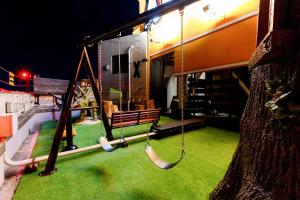 an outdoor playground with swings and a tree at HOTEL ARTIA DINOSAUR MACHIDA -Adult Only in Kami-seya