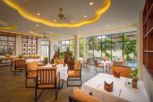 a restaurant with white tables and chairs and windows at Model Temple Villa in Siem Reap