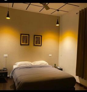 a bedroom with a large bed with two lights at Premier Lodge in Dimāpur