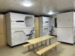 a room with white appliances and a table and a bench at Efate Motel in Port Vila