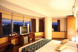 una camera d'albergo con letto e TV di Hotel Oval a Surabaya