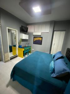 a bedroom with a blue bed and a living room at SUITES FullHouse in Guayaquil