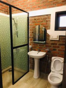 un bagno con lavandino, servizi igienici e muro di mattoni di Euro star holiday inn a Wennappuwa