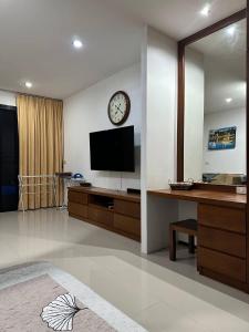 sala de estar con TV y reloj en la pared en Apartment en Ban Mae Nam