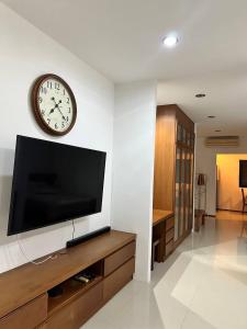 a living room with a tv and a clock on the wall at Apartment in Ban Mae Nam