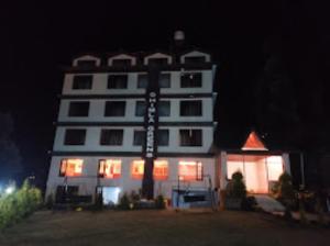 - un grand bâtiment blanc avec un panneau devant dans l'établissement Shimla Greens Shimla, à Shimla