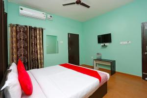 a bedroom with a white bed with red pillows at Flagship The Maple Tree Hotels in Bhubaneshwar