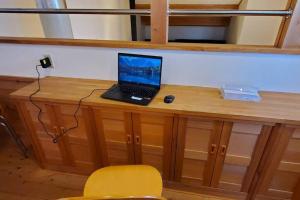 un ordinateur portable installé au-dessus d'un bureau en bois dans l'établissement 都留市エコハウスで移住体験を, à Tsuru 