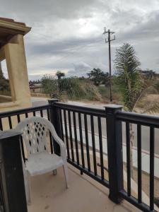 une chaise blanche assise sur un balcon donnant sur une rue dans l'établissement Pacific Plaza Resort, à Oceano