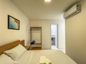 a bedroom with a white bed and a fan at Ap novo em frente a shopping center e próximo a praia in Vila Velha