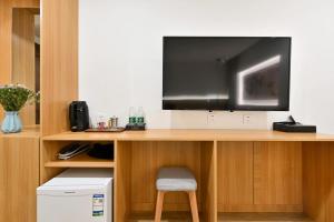 a tv sitting on a wooden desk with a chair at Xingshe Alley Courtyard Hotel Beijing Wangfujing Forbidden City Branch in Beijing