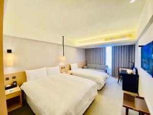 una camera d'albergo con due letti e una televisione di Inn by the Village a Città di Taitung