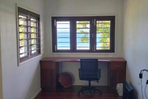 een bureau met een stoel in een kamer met 2 ramen bij Dream Cove Cottage, 2 Bedroom in Port Vila