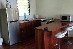 a kitchen with a stainless steel refrigerator and wooden cabinets at Dream Cove Cottage, 2 Bedroom in Port Vila