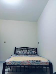 Bett in einem Zimmer mit einer weißen Wand in der Unterkunft Vintage Apartment in Abu Dhabi