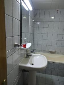 een witte badkamer met een wastafel en een spiegel bij Vintage Apartment in Abu Dhabi