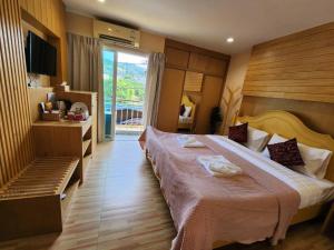 パトンビーチにあるAlaita Hostel Patongの大型ベッドとテレビが備わるホテルルームです。