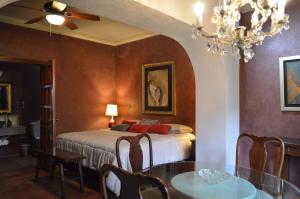 een slaapkamer met een bed, een tafel en een kroonluchter bij Hotel Art Gallery Casona de los Milagros in Colima