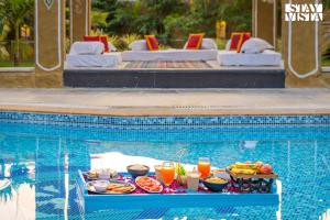 a tray of food on a table in a swimming pool at StayVista's Majestic Mud House - Rajasthani Architecture with Modern Amenities, Outdoor Pool, Adventure Activities, and Spa in Pushkar