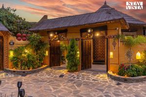 a house with a courtyard with plants in front of it at StayVista's Majestic Mud House - Rajasthani Architecture with Modern Amenities, Outdoor Pool, Adventure Activities, and Spa in Pushkar