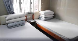 two stacks of pillows sitting on a bed in a room at OYO 90914 Hotel Mei Wah in Kampong Selanchor