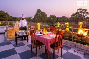 a chef standing on a deck with a table and chairs at StayVista's Majestic Mud House - Rajasthani Architecture with Modern Amenities, Outdoor Pool, Adventure Activities, and Spa in Pushkar
