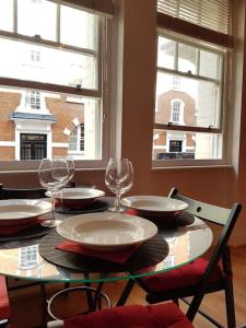 a table with glasses and plates on it with two windows at Cozy Flat, 5 minute walk to Oxford Circus in London