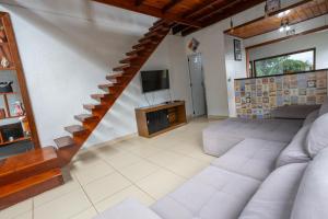 ein Wohnzimmer mit einer Treppe und einem TV in der Unterkunft Rec. Harmonia Wi-Fi Piscina Churrasqueira Lareira in Juquitiba