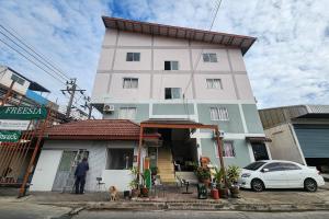 北榄Freesia Bangphi Guest House的一名男子站在一栋建筑物前
