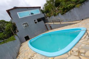 a blue swimming pool in front of a house at Rec. Harmonia Wi-Fi Piscina Churrasqueira Lareira in Juquitiba