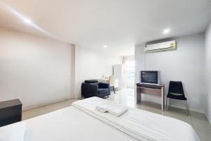 a white room with a bed and a desk and a tv at Freesia Bangphi Guest House in Samutprakarn