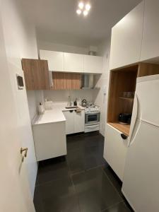 cocina con armarios blancos y nevera blanca en Apartamento Malabia en Buenos Aires