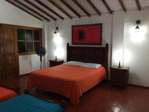 a bedroom with a bed with orange sheets and two lamps at Finca El Sueño De Mi Abuelo in Pereira +132 photos