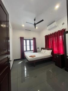 a bedroom with a bed and red curtains at RAJAGIRI Heaven in Alwaye