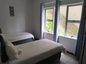 two beds in a room with a window at 5 Telena in Umdloti