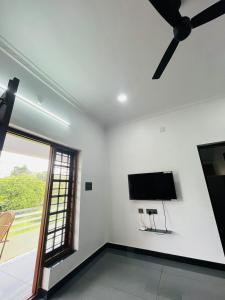 uma sala de estar com uma ventoinha de tecto e uma televisão de ecrã plano em RAJAGIRI Heaven em Alwaye