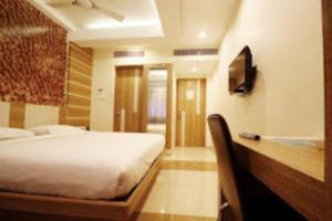 um quarto com uma cama e uma televisão na parede em Hotel SBS Grand , Coimbatore em Coimbatore