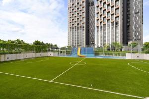 a tennis court with a green field and buildings at 2-Bedroom Condominium in LUMI TROPICANA in Petaling Jaya